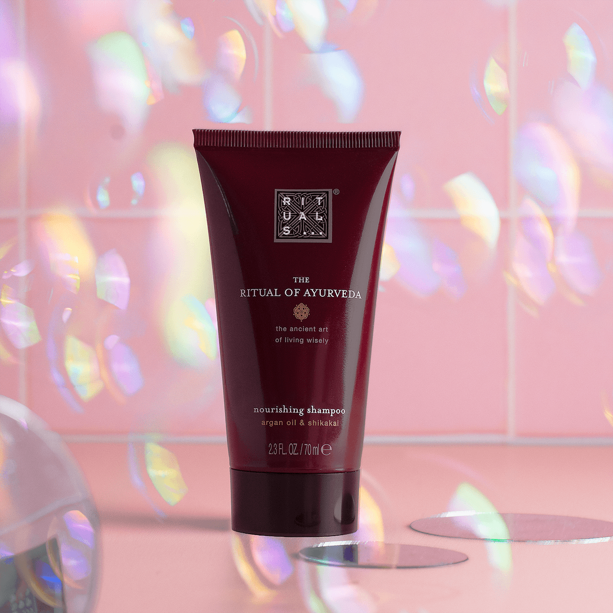 Rituals shampoo surrounded by iridescent reflections on a pink set