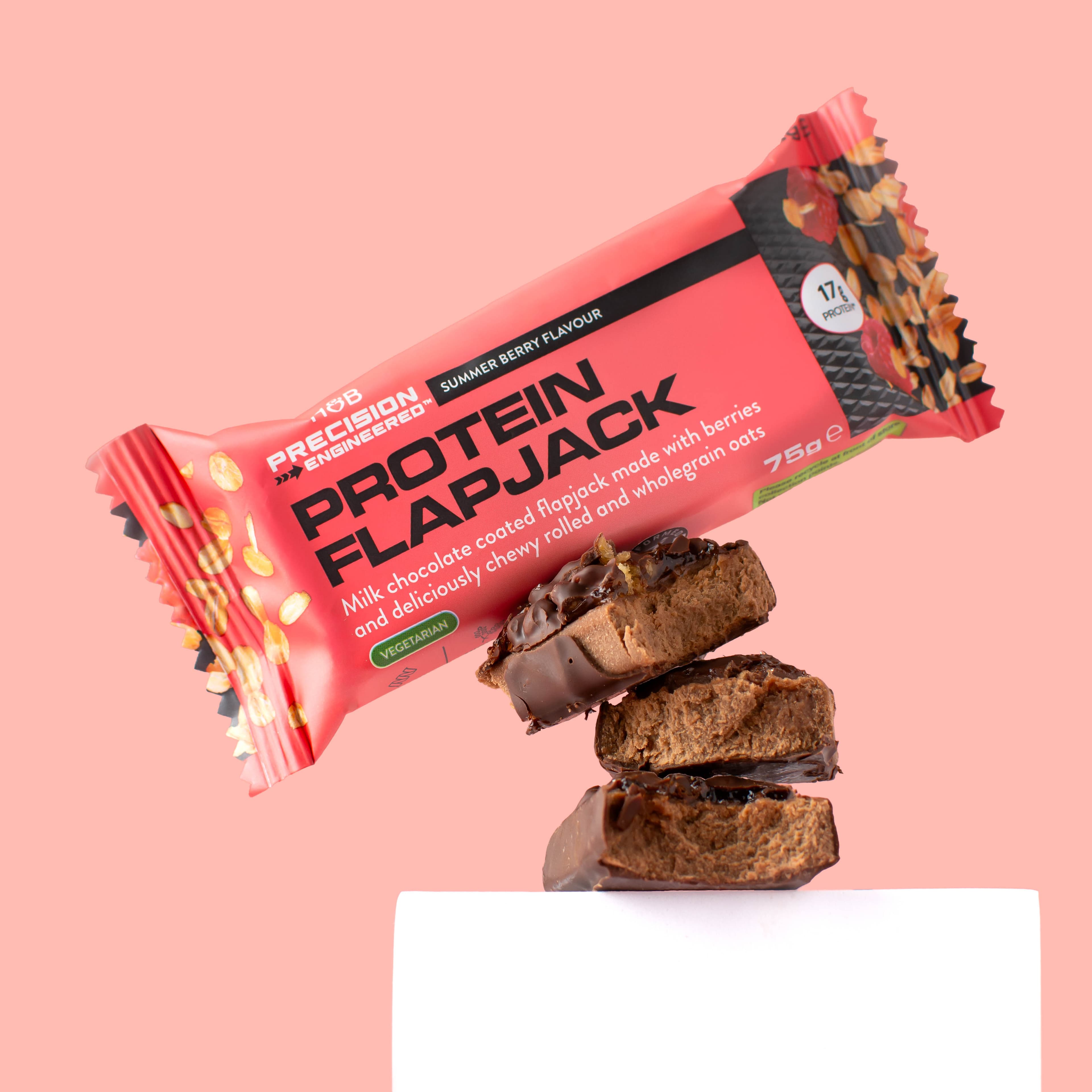 Protein flapjack packaging with stacked chocolate pieces against pink