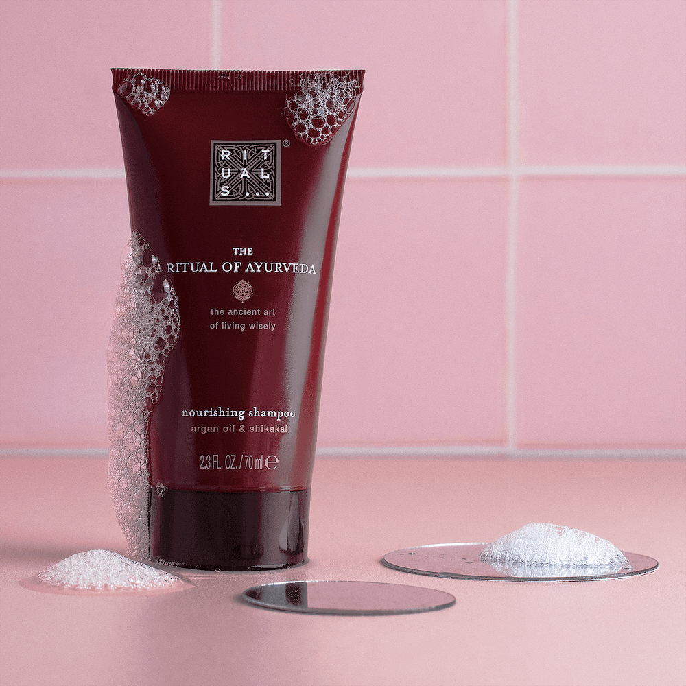 Rituals product tube beside a small mound of powder on pink tiles