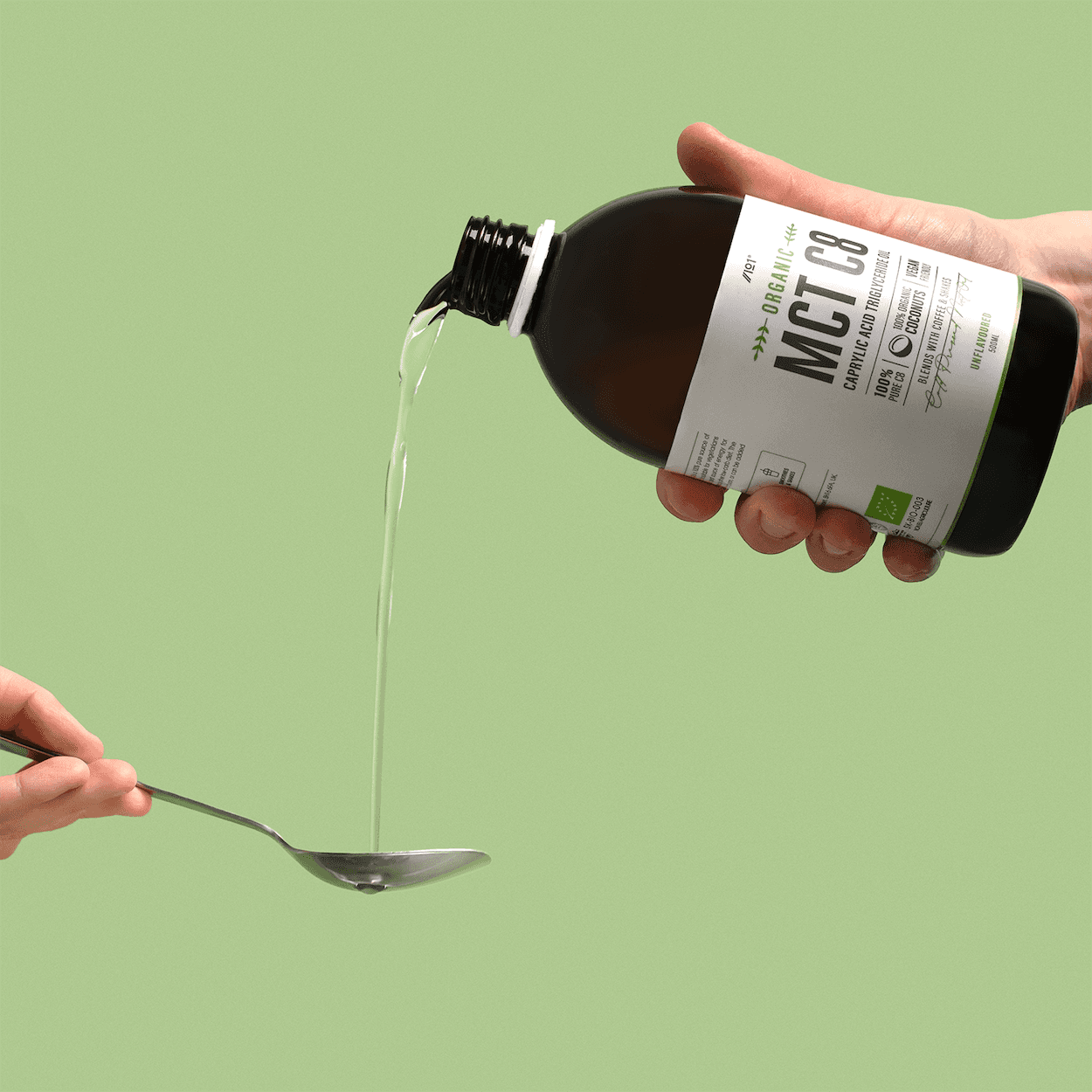 Liquid supplement being poured from a bottle against a green background