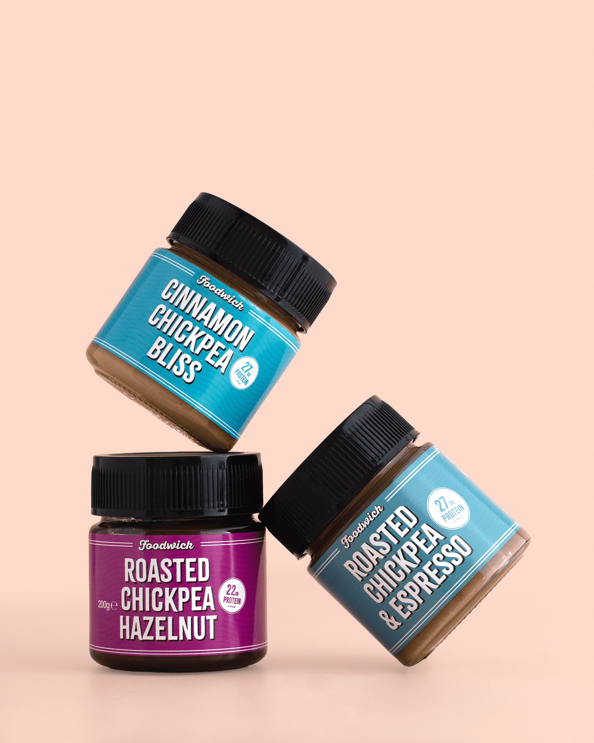 Four jars of chickpea and hazelnut spreads balanced against peach