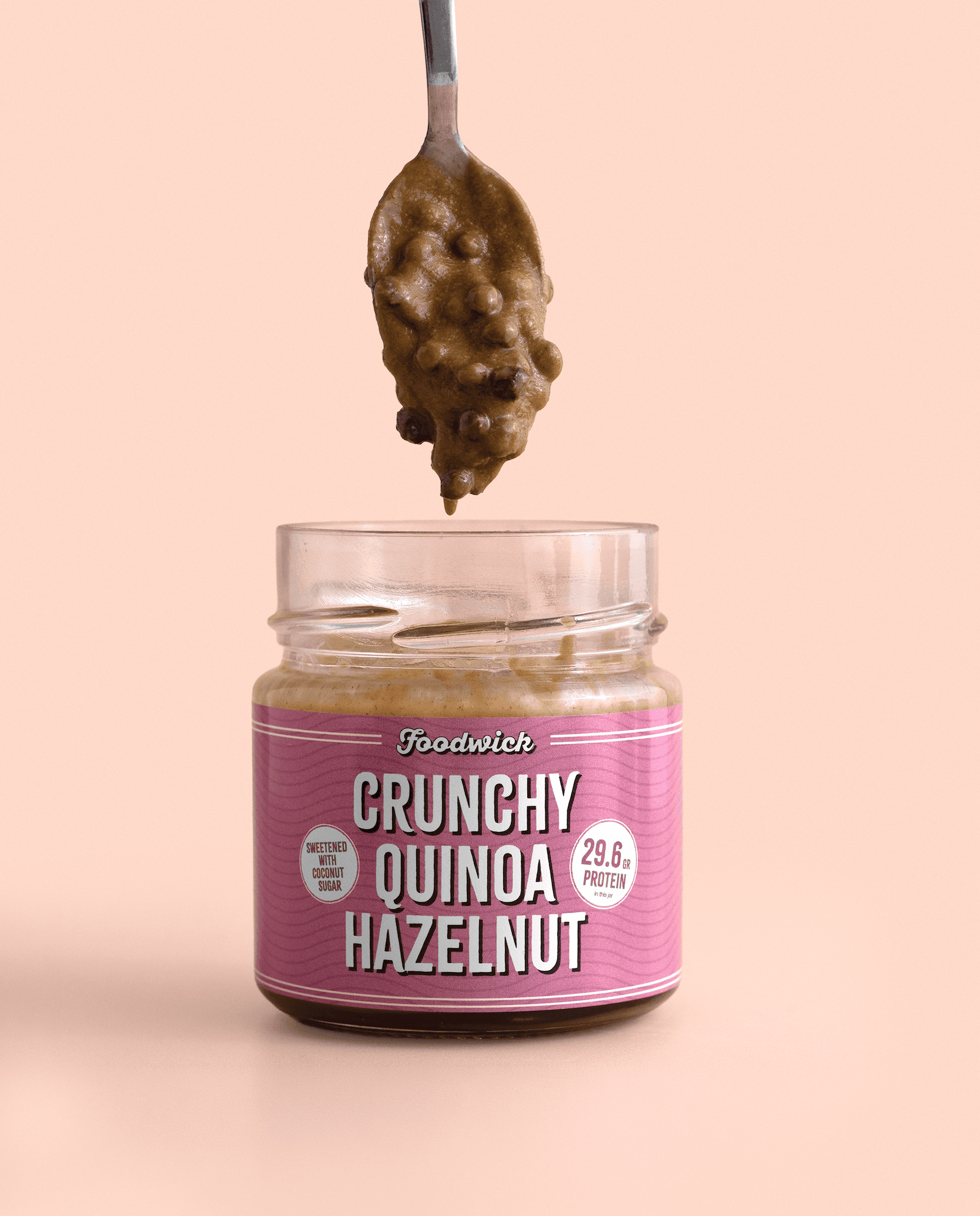 Spoon of crunchy quinoa and hazelnut spread above an open jar