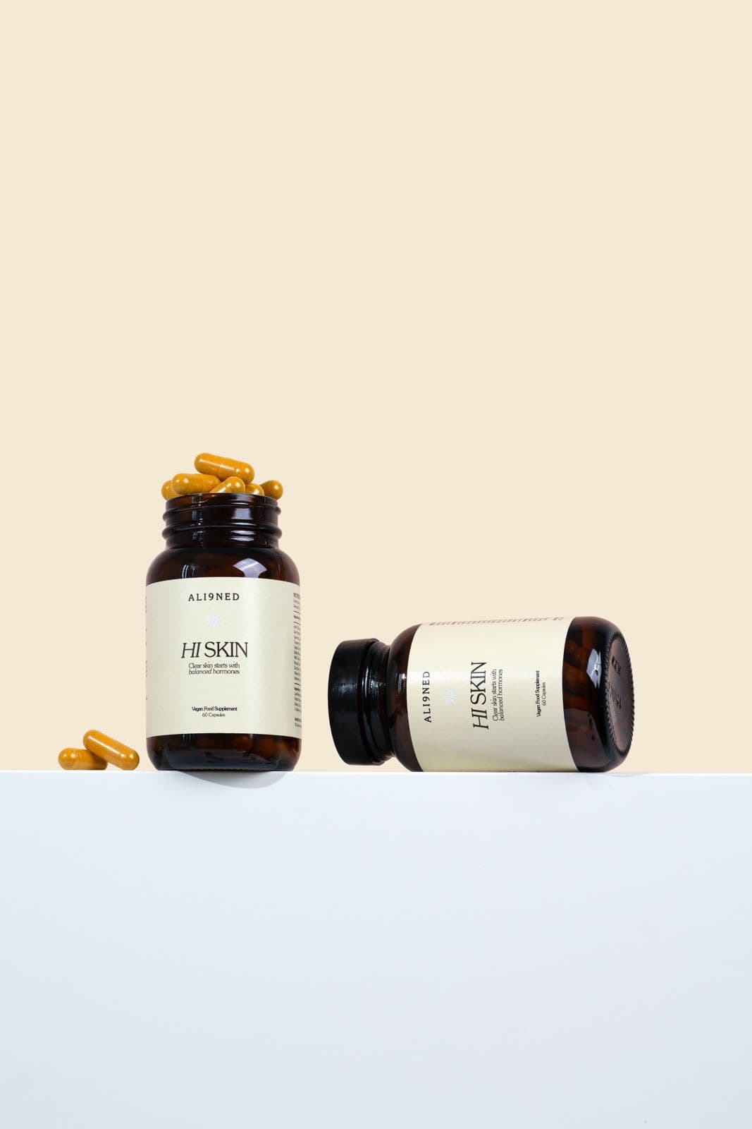 Supplement bottles and golden capsules on a cream and white set