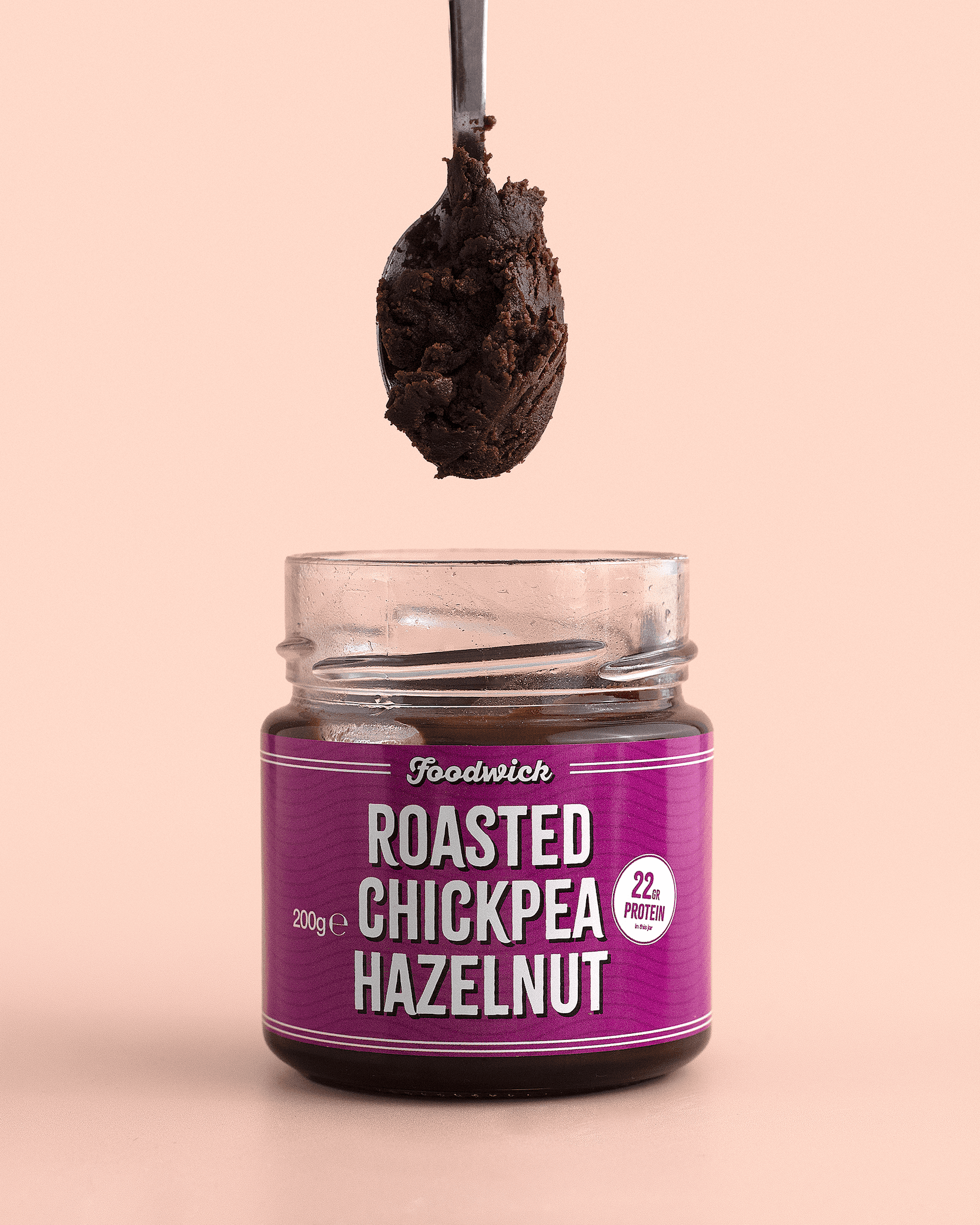 Spoon of roasted chickpea and hazelnut spread above its jar