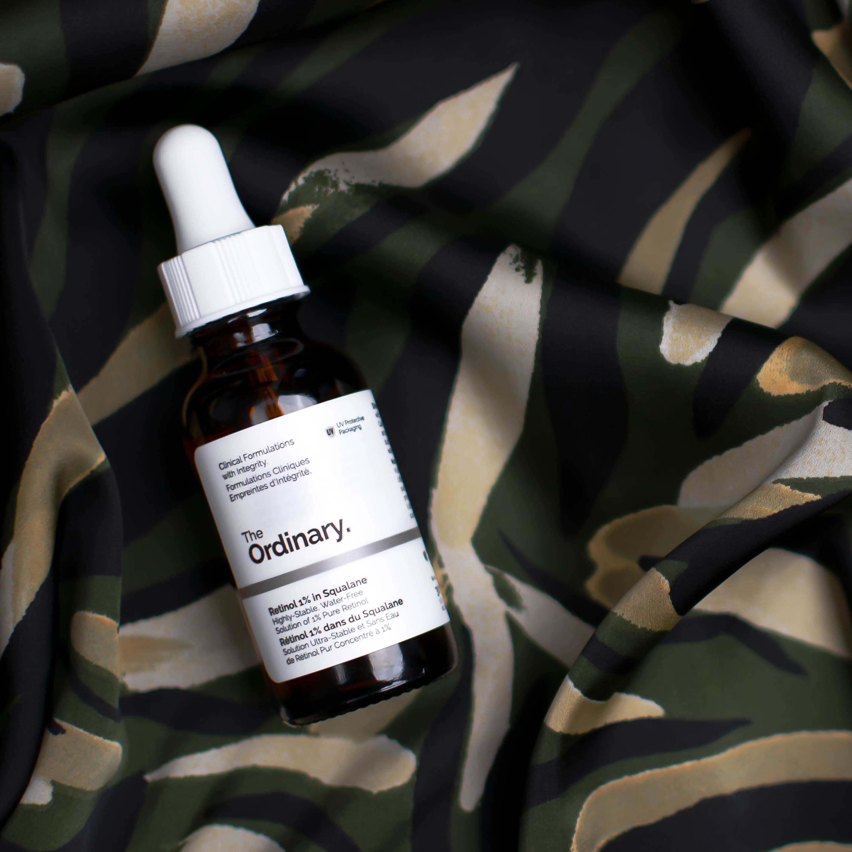 The Ordinary serum bottle among leaves and patterned shadows