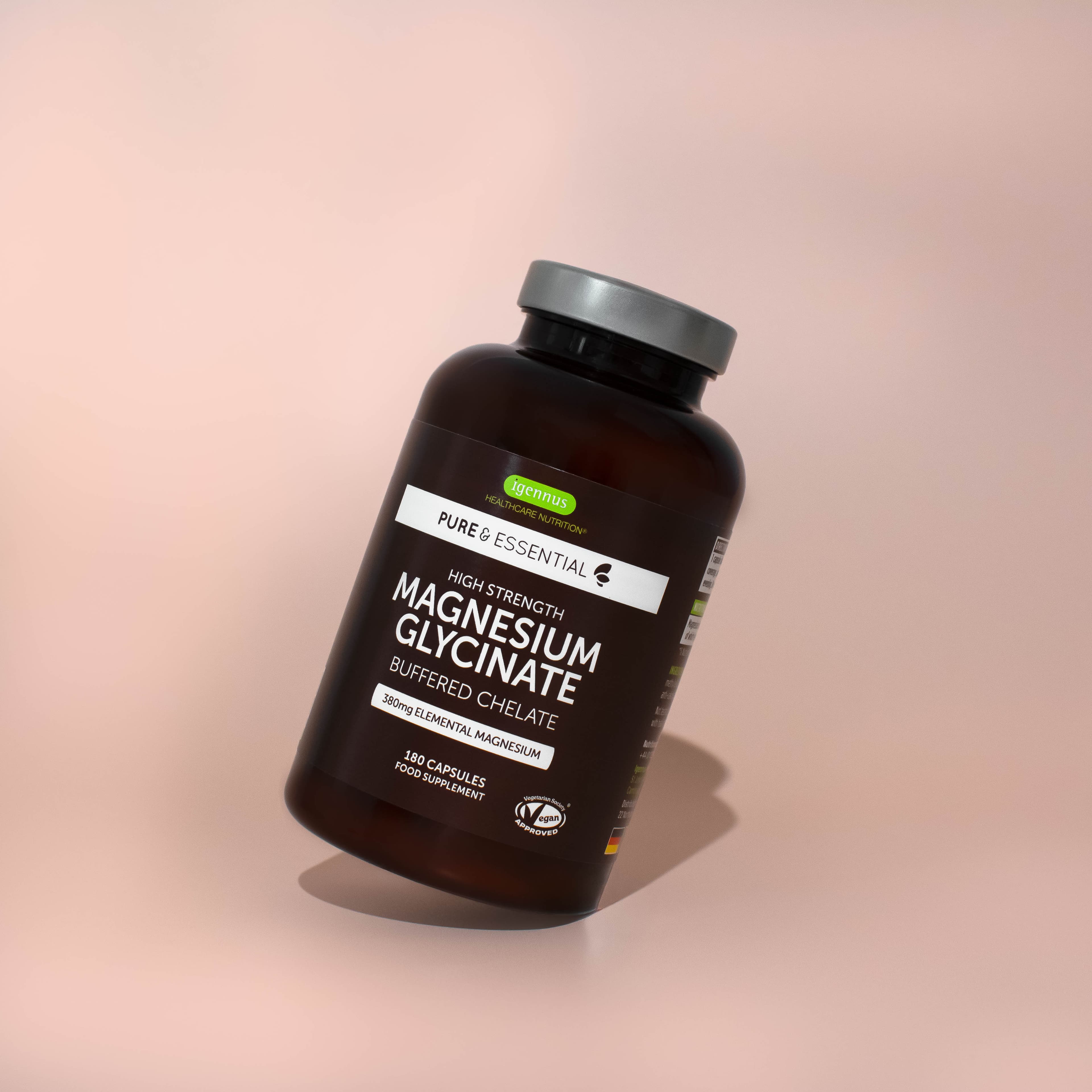 Magnesium supplement bottle casting a shadow on a pink background