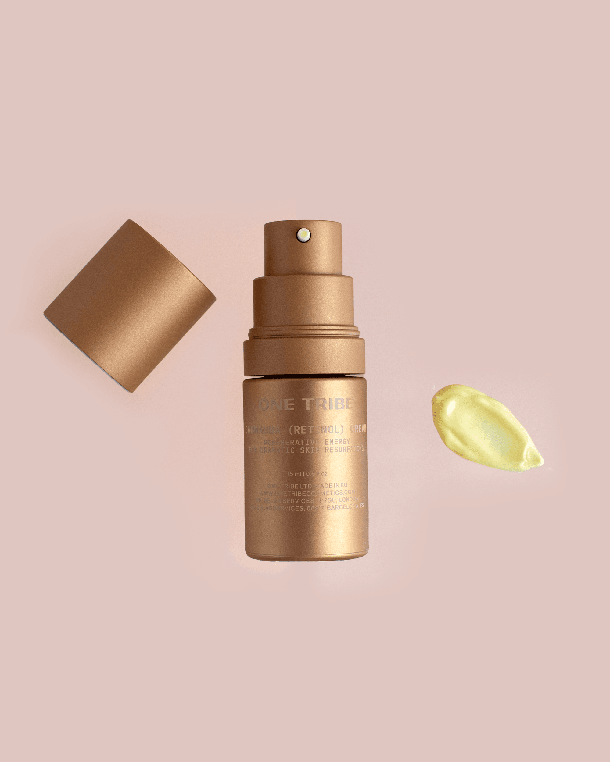 Gold skincare bottle with its cap and a drop of serum