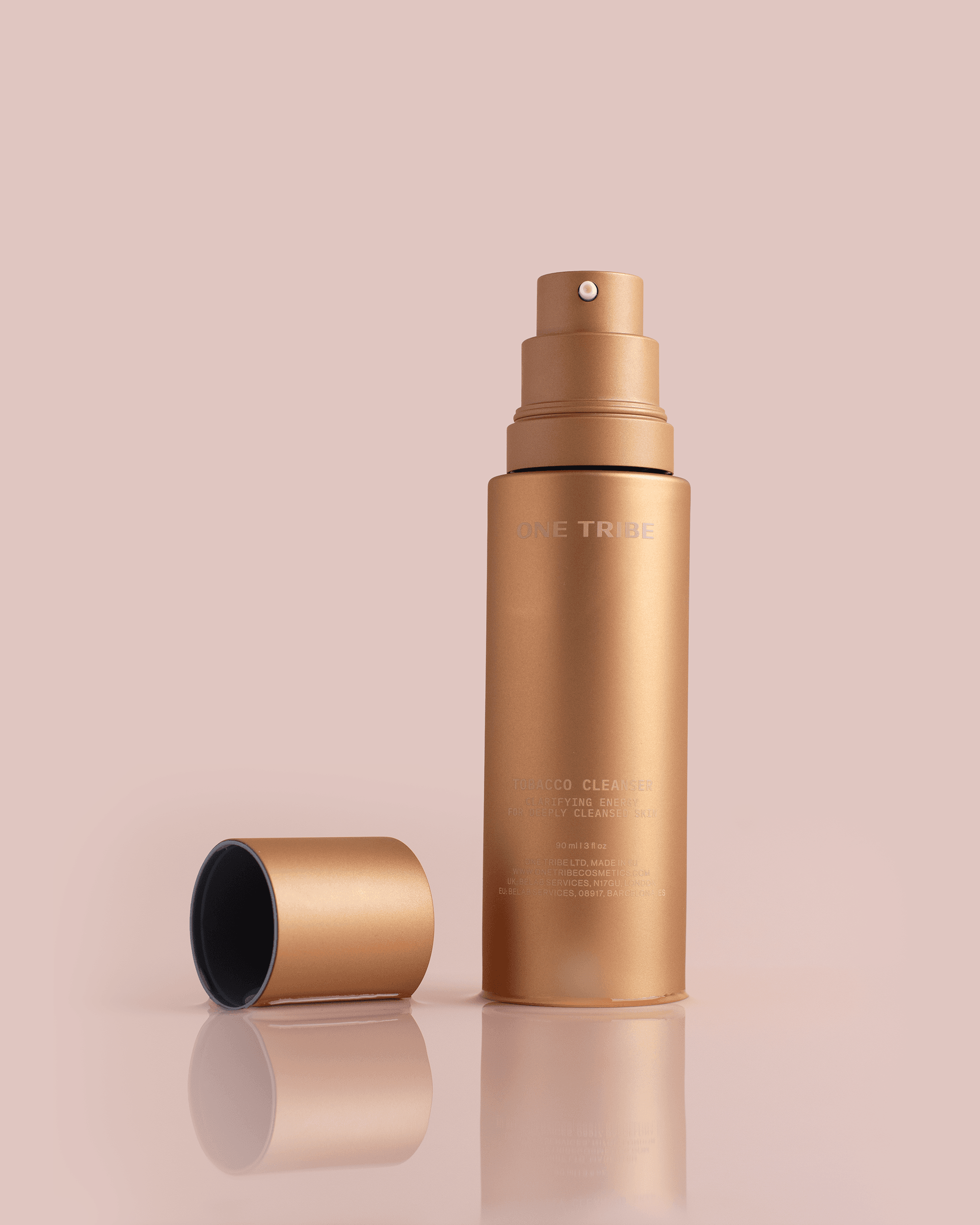 Gold skincare spray bottle standing beside its cap