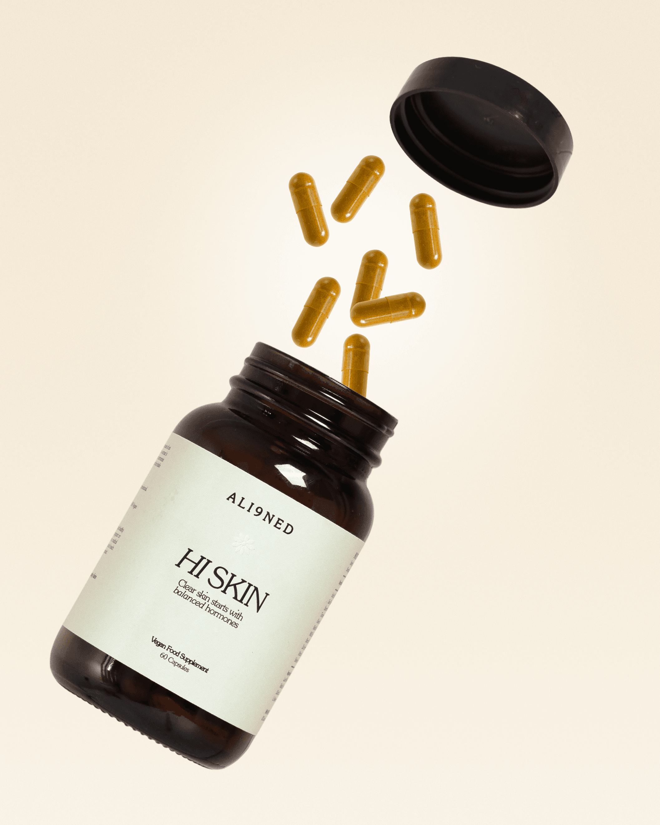Supplement bottle with its lid and golden capsules suspended above it